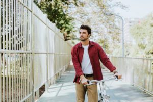 One caucasian man pushing his bicycle at park